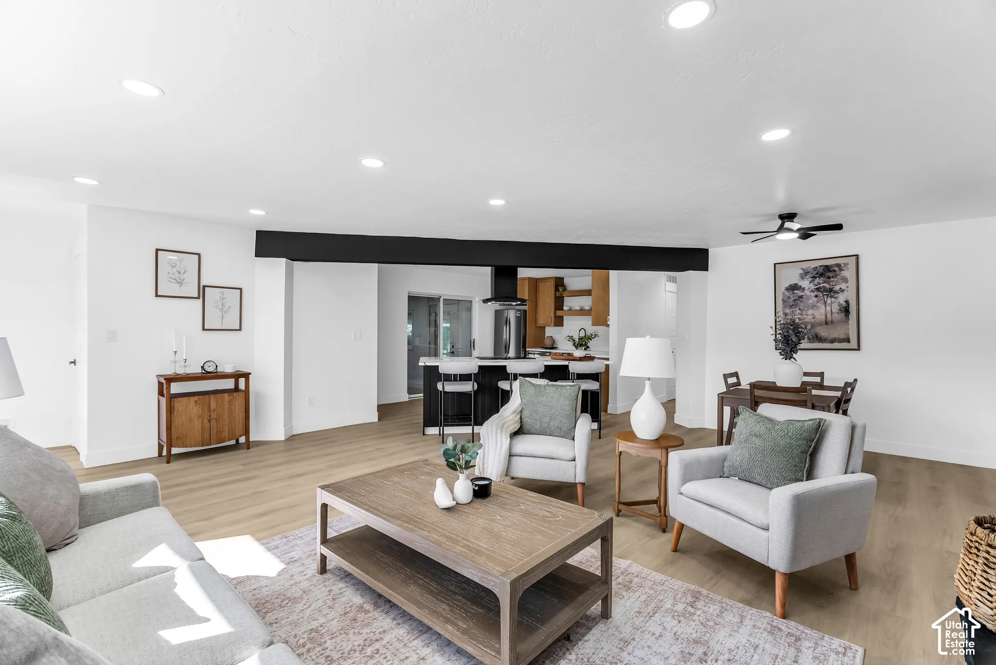 Open floor plan featuring wood-finish flooring, recessed lighting, and a prominent horizontal structural beam