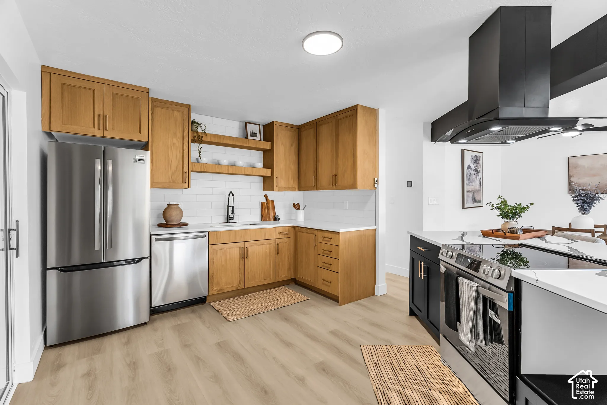 Kitchen featuring wood cabinetry, stainless steel appliances, white subway tile backsplash, matte black range hood, and wood-finish flooring