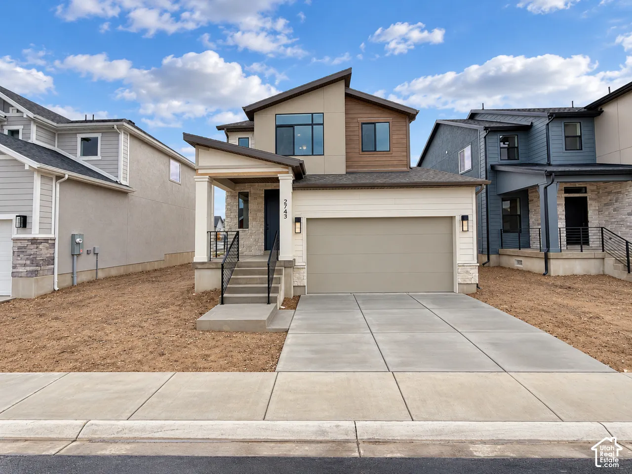 Contemporary exterior featuring stone veneer accents, wood-finish paneling, concrete driveway, and covered front porch with metal railing