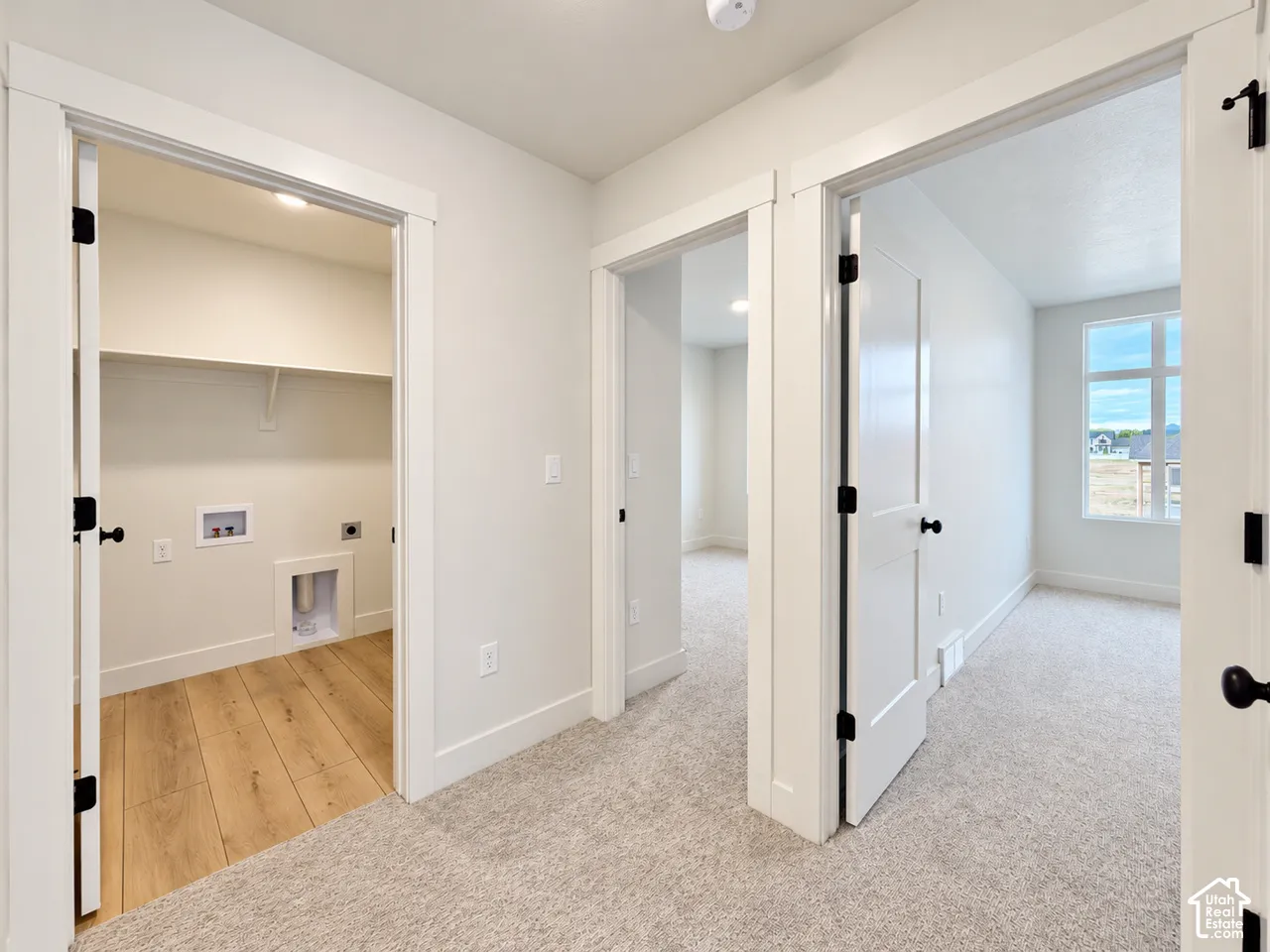 Laundry room featuring wood-finish flooring, a built-in shelf, and recessed lighting, accompanied by two rooms finished with wall-to-wall carpeting and multi-panel doors with matte black hardware