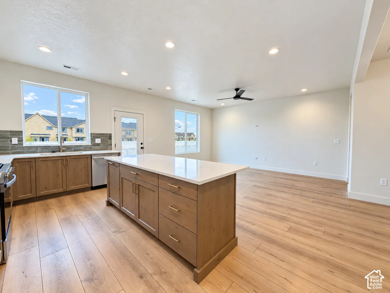 Kitchen featuring a large center island with a stone countertop, wood-finish cabinetry, recessed lighting, wood-finish flooring, and a tile backsplash