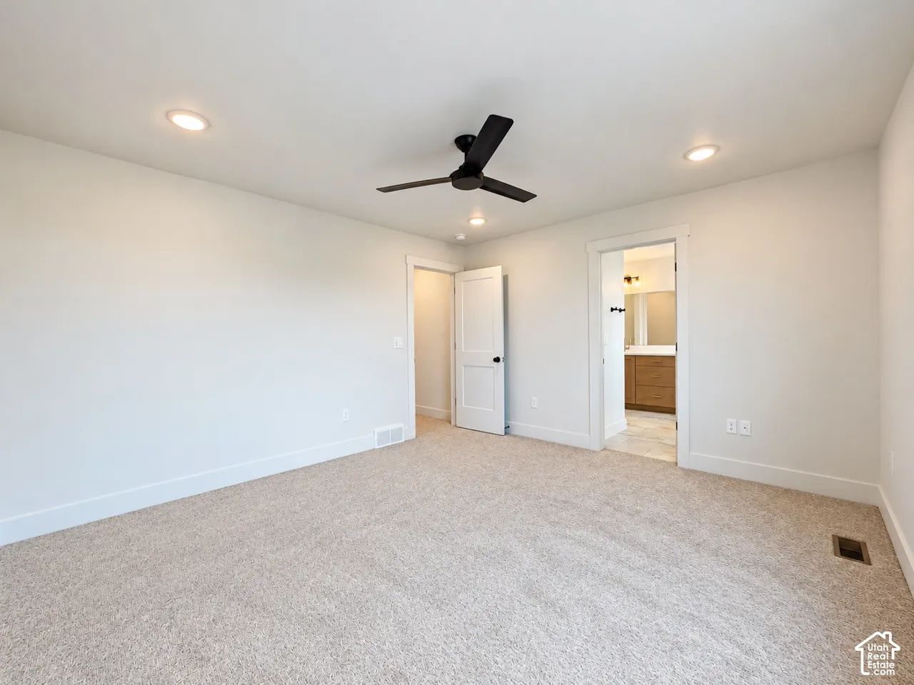 Neutral carpeting, recessed lighting, matte black ceiling fan, and paneled interior doors