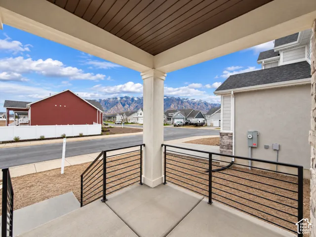 Covered entryway featuring a concrete porch, metal railing, recessed wood-finish ceiling, and mountain backdrop