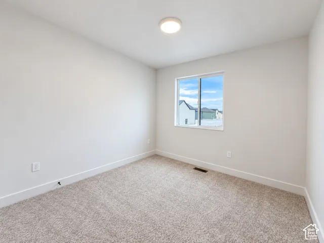 Neutral-toned walls, plush wall-to-wall carpeting, single-pane sliding window, and a flush-mount ceiling light fixture