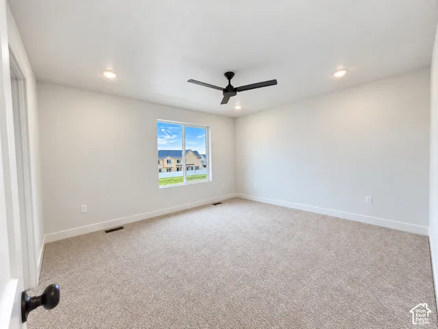Neutral-toned wall-to-wall carpeting, recessed ceiling lighting, and a matte black ceiling fan