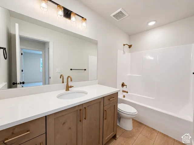 Bathroom featuring wood-finish cabinetry, white countertop with an integrated basin, brushed metal fixtures, large wall-mounted mirror, and wood-finish flooring
