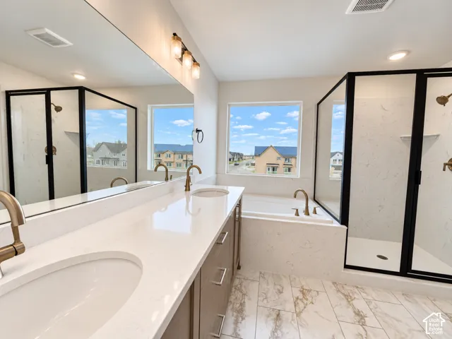Dual-sink vanity with quartz countertops and wood-finish cabinetry, porcelain-tiled flooring, soaking tub, and a glass-enclosed shower with matte black fixtures