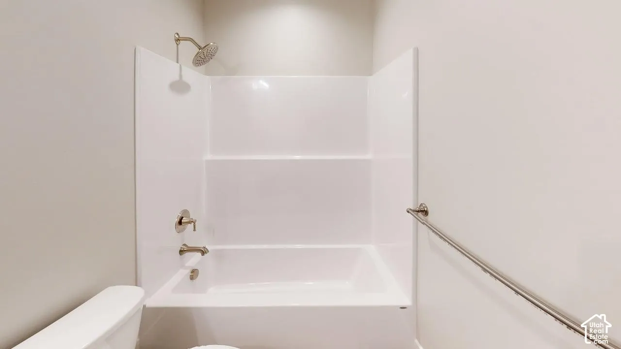 Bathtub with integrated surround, chrome finish shower head, chrome finish tub faucet, and wall-mounted chrome finish grab bar