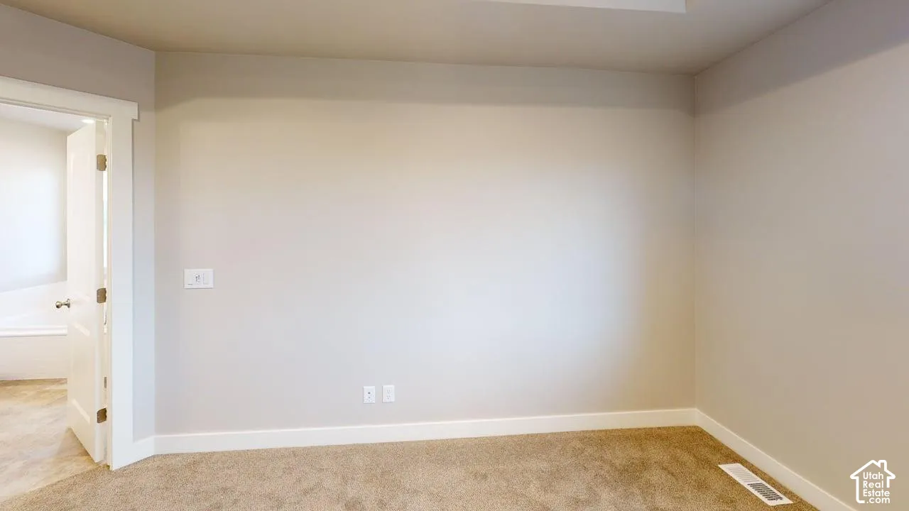 Neutral-toned interior space featuring carpeted flooring and a paneled interior door