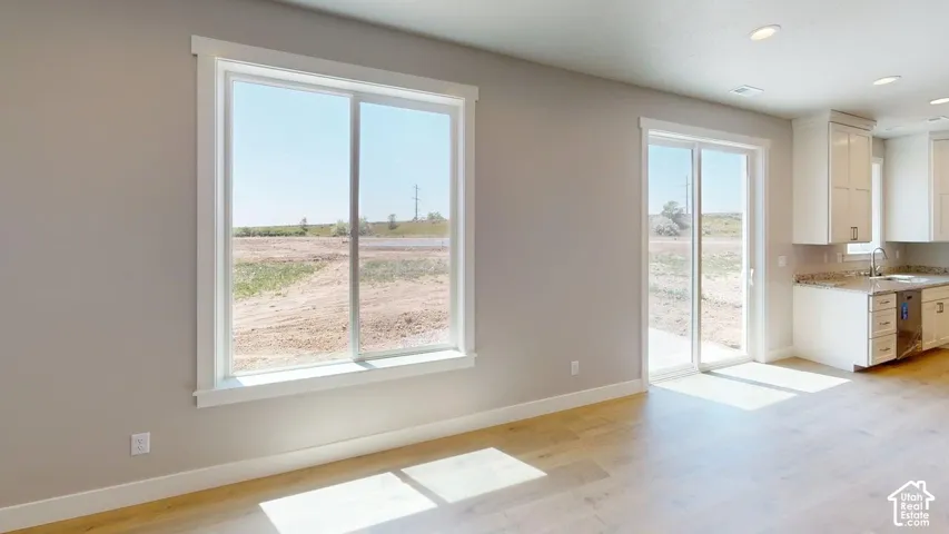 Light-toned wood-finish flooring, sliding glass door, oversized windows with trim, and built-in white cabinetry with stone-finish countertops