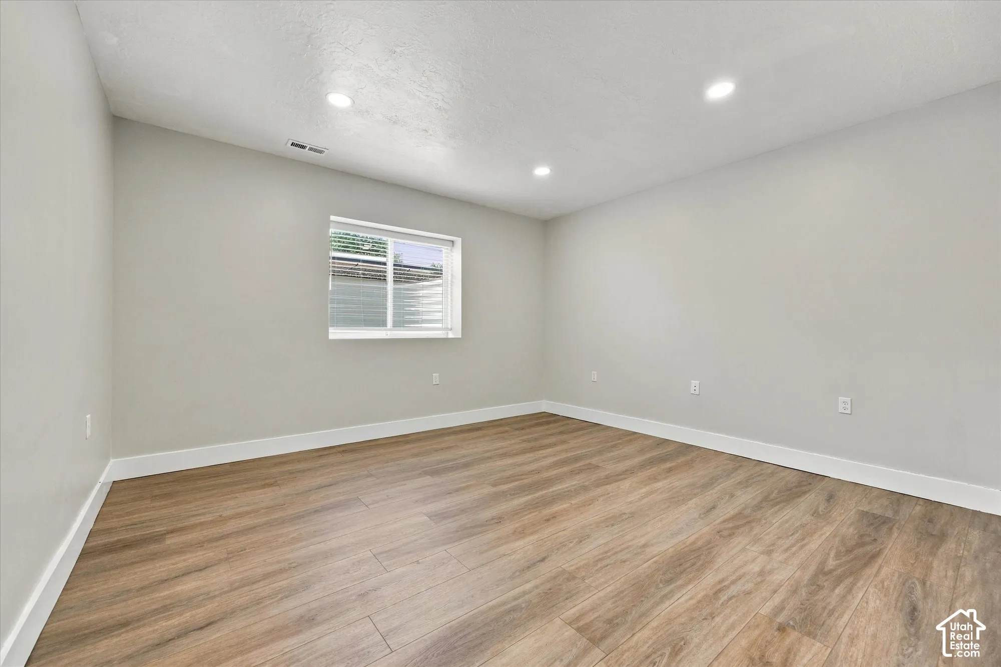 Room featuring wood-finish flooring, neutral wall paint, recessed lighting, and a single-pane window