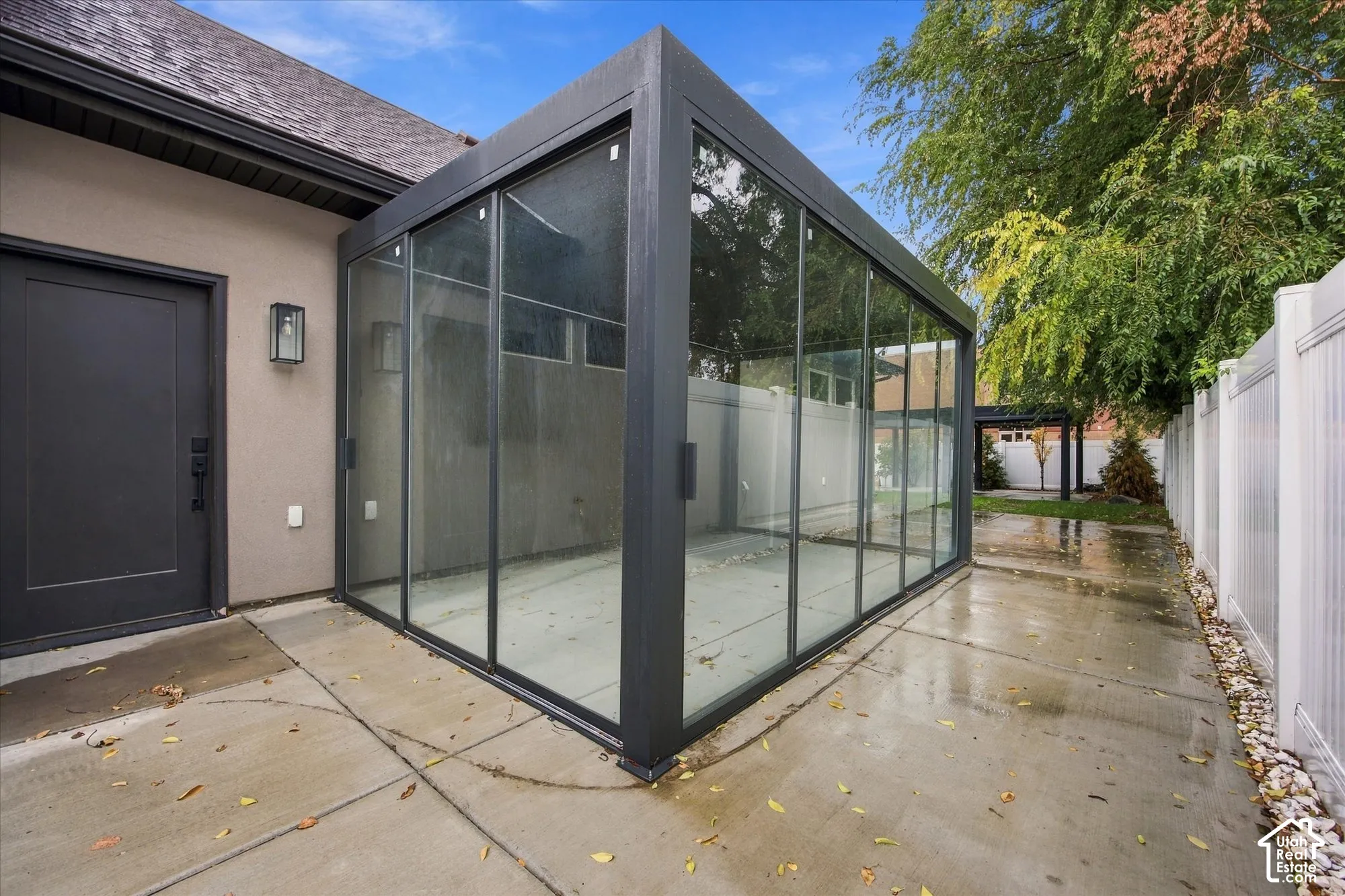 Enclosed glass sunroom with a dark-finished metal frame and concrete patio flooring