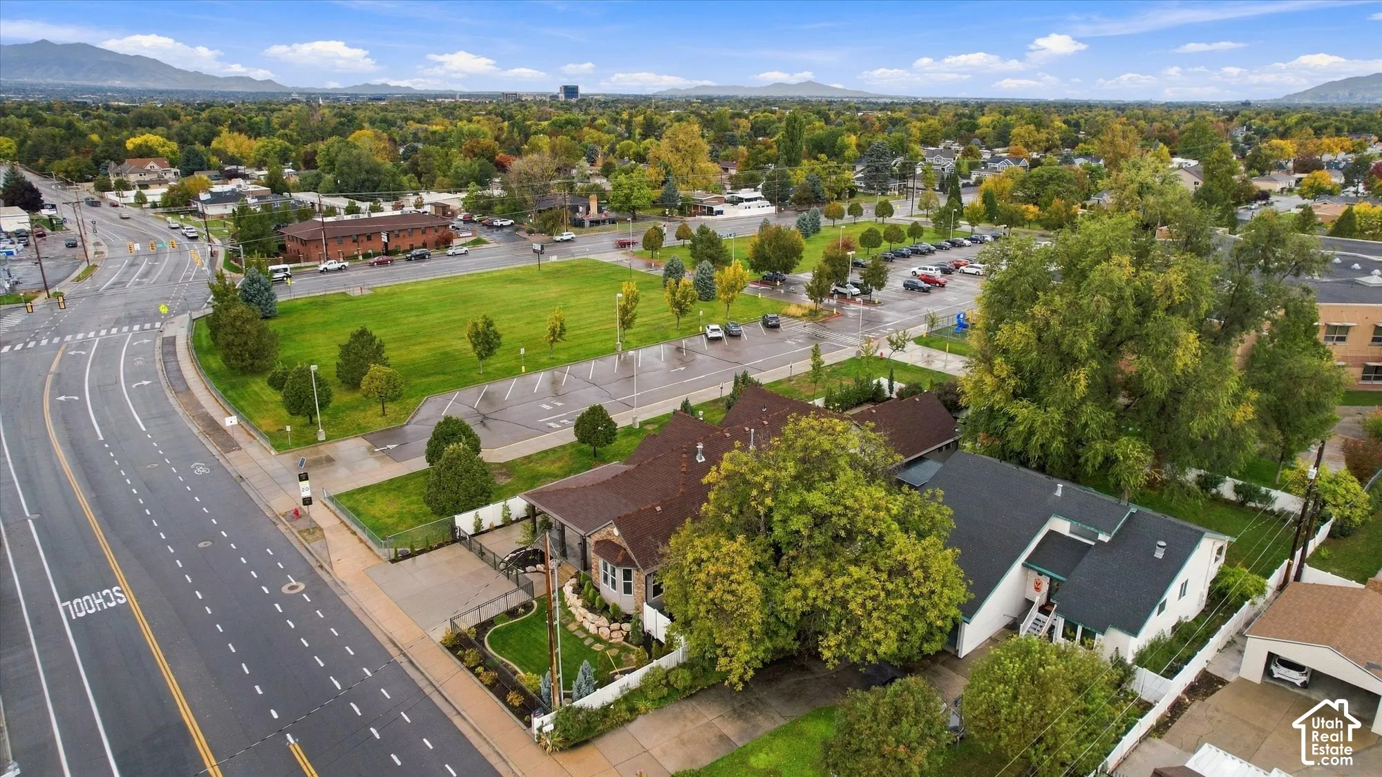 Aerial perspective showcasing a residential lot with mature trees, a manicured lawn, stone landscaping accents, and a fenced perimeter