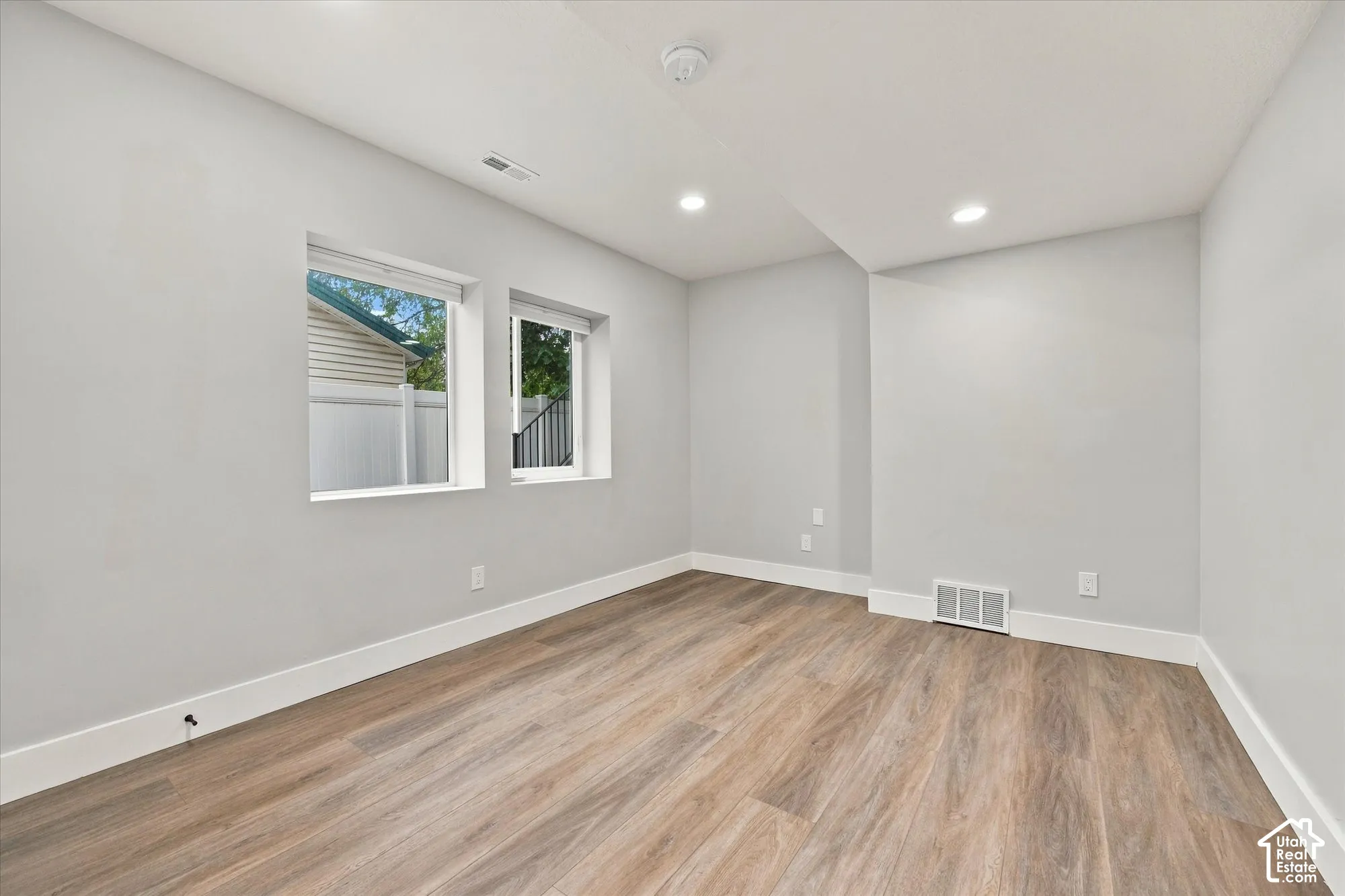 Neutral-toned interior room featuring wood-finish flooring, recessed lighting, and double windows