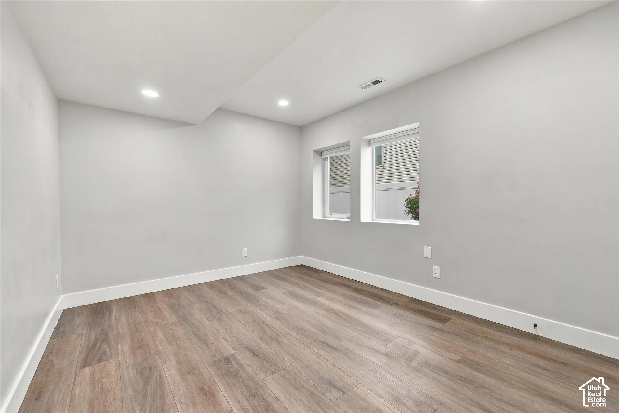Neutral interior space featuring wood-finish flooring, recessed lighting, and dual inset windows
