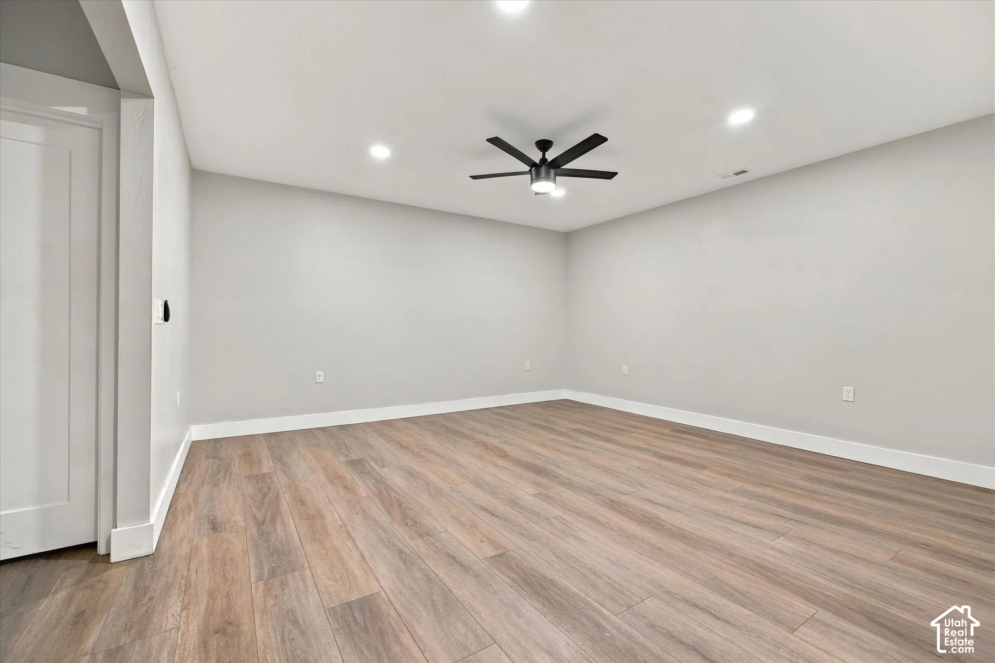 Interior room featuring wood-finish flooring, recessed lighting, and a matte black ceiling fan with an integrated light fixture