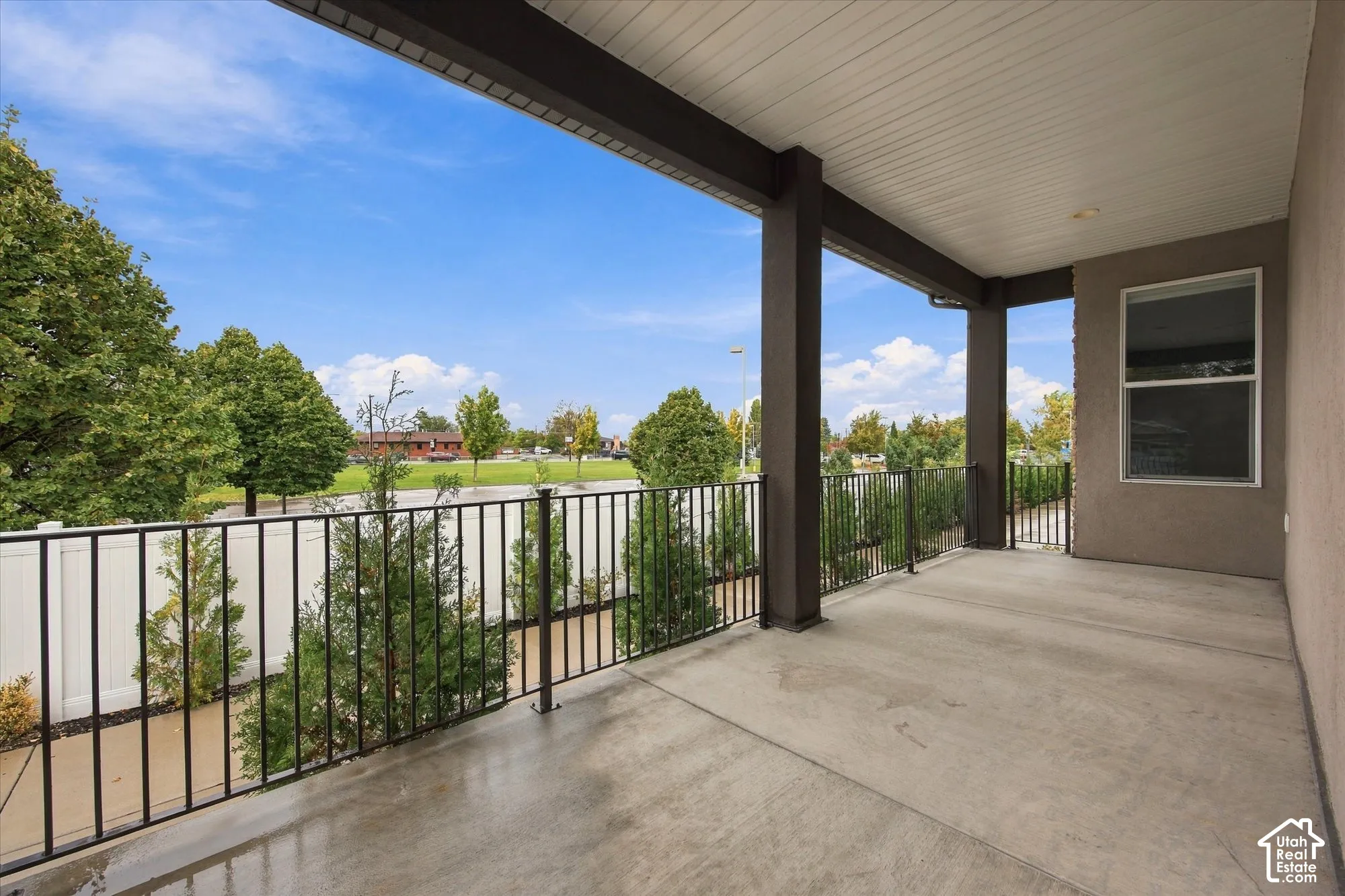 Covered patio featuring concrete flooring, a beadboard ceiling, square support pillars, and metal railing