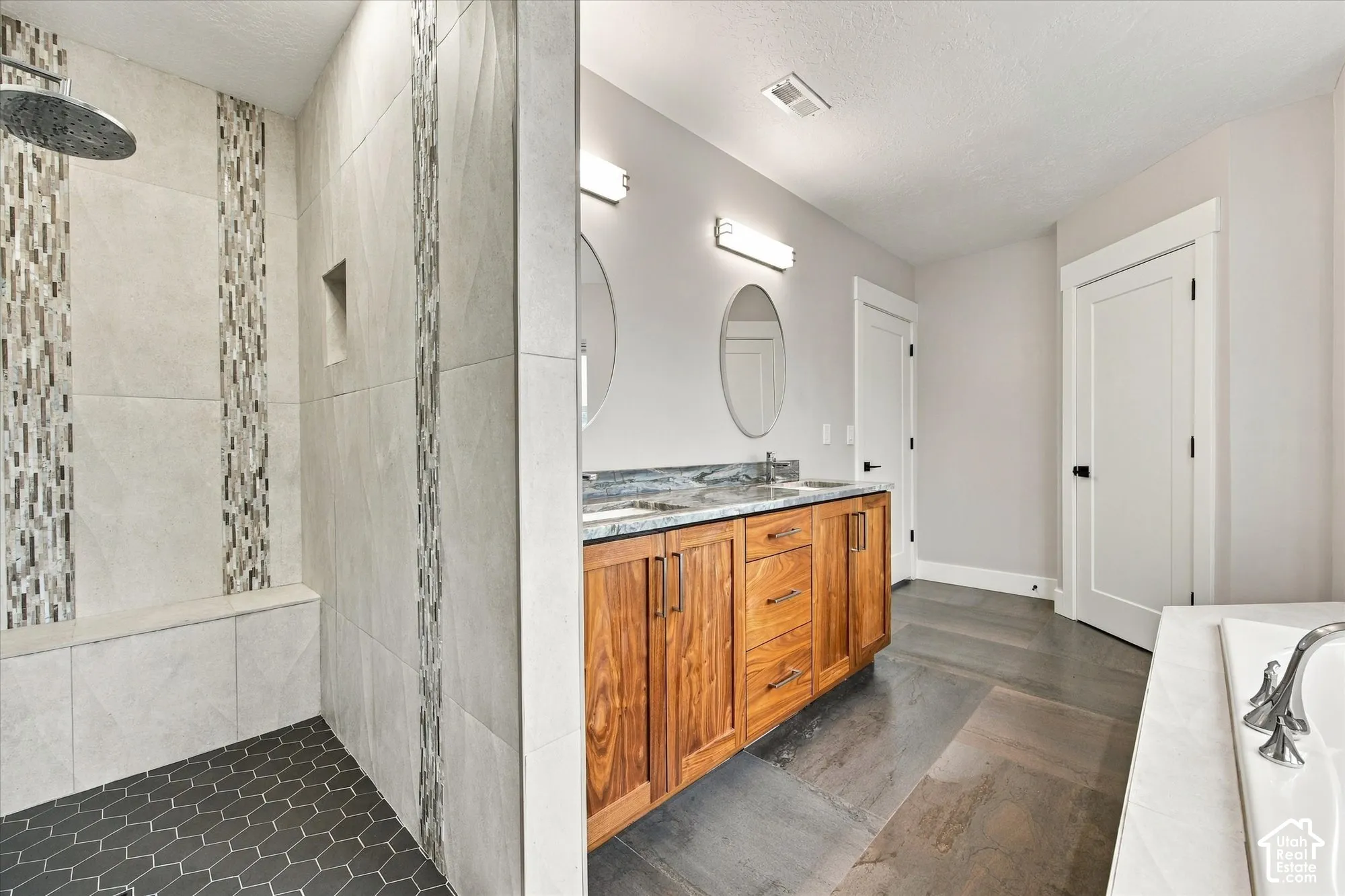 Walk-in shower with stone tile surround, integrated mosaic accent tiling, and built-in bench