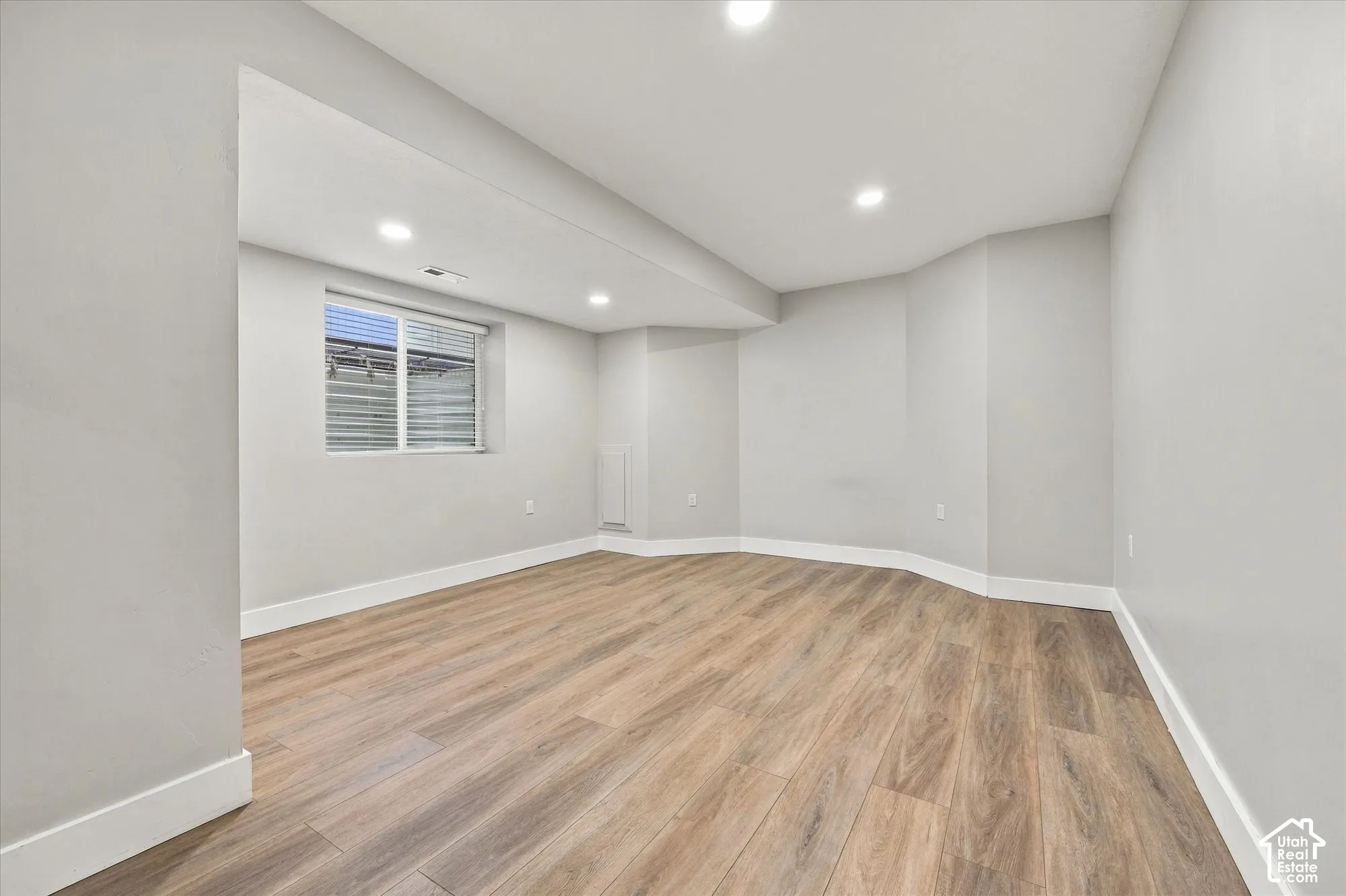Interior room featuring neutral wall paint, wood-finish flooring, recessed lighting, and a single-pane sliding window