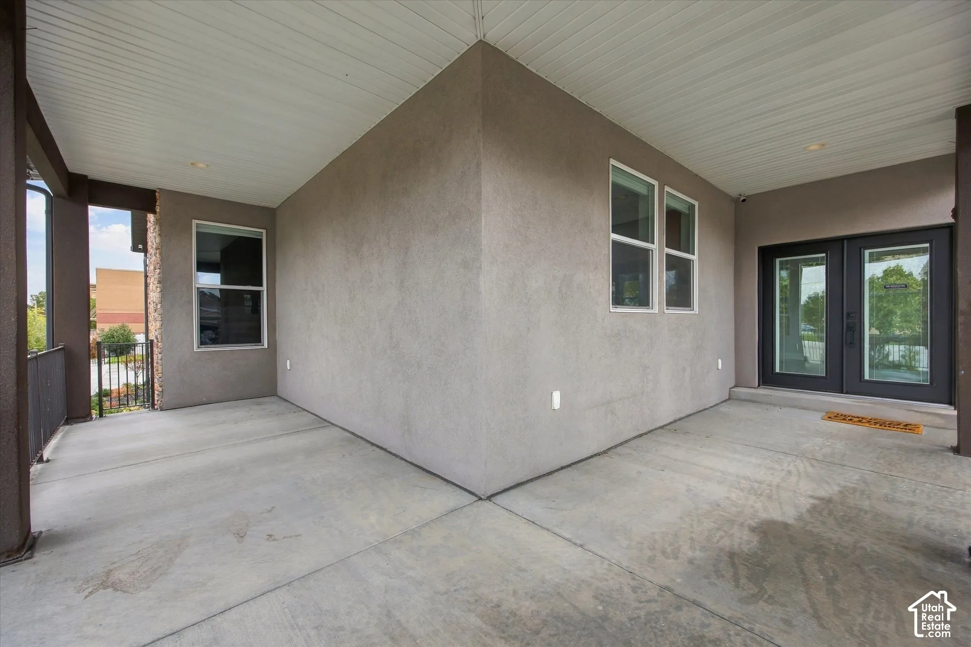 Covered porch featuring concrete flooring, stucco siding, recessed lighting, and double-entry doors with glass panels