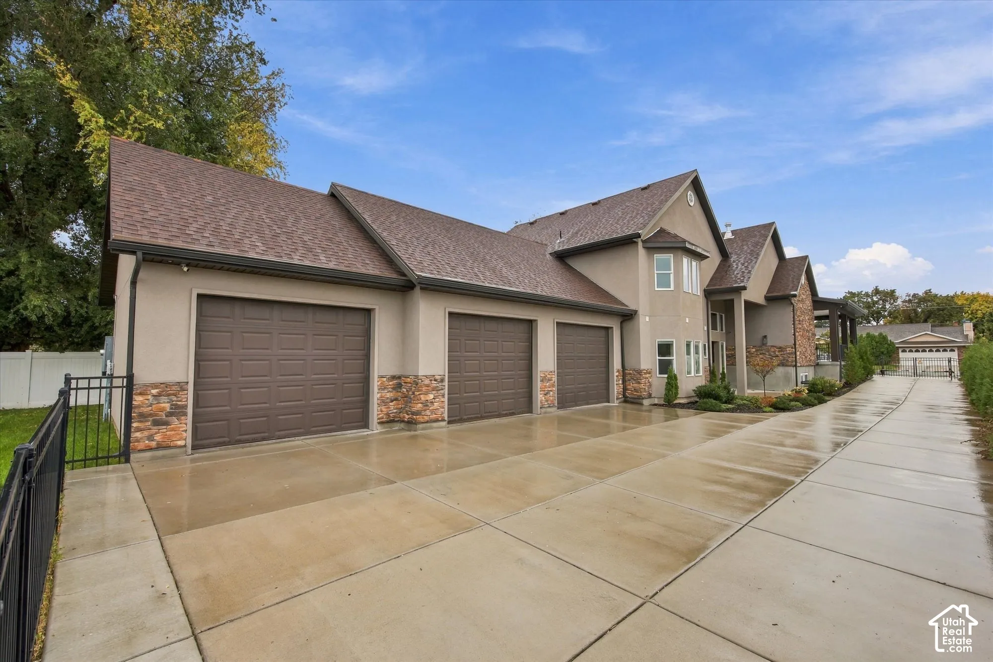 Multi-level exterior featuring a three-car garage, stone veneer accents, multi-gabled roofline, and an expansive concrete driveway