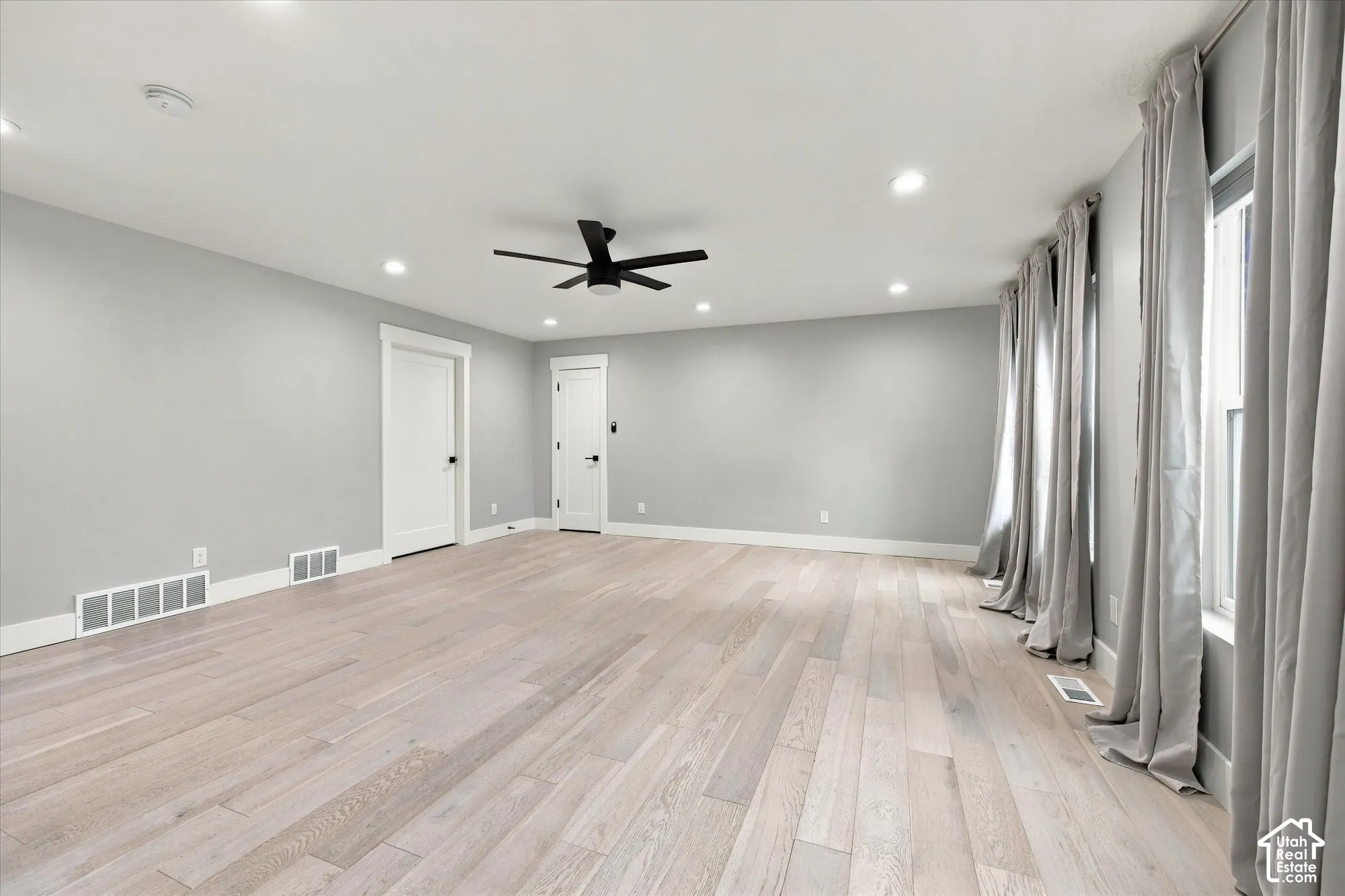 Spacious room featuring wood-finish flooring, recessed lighting, and a modern black ceiling fan