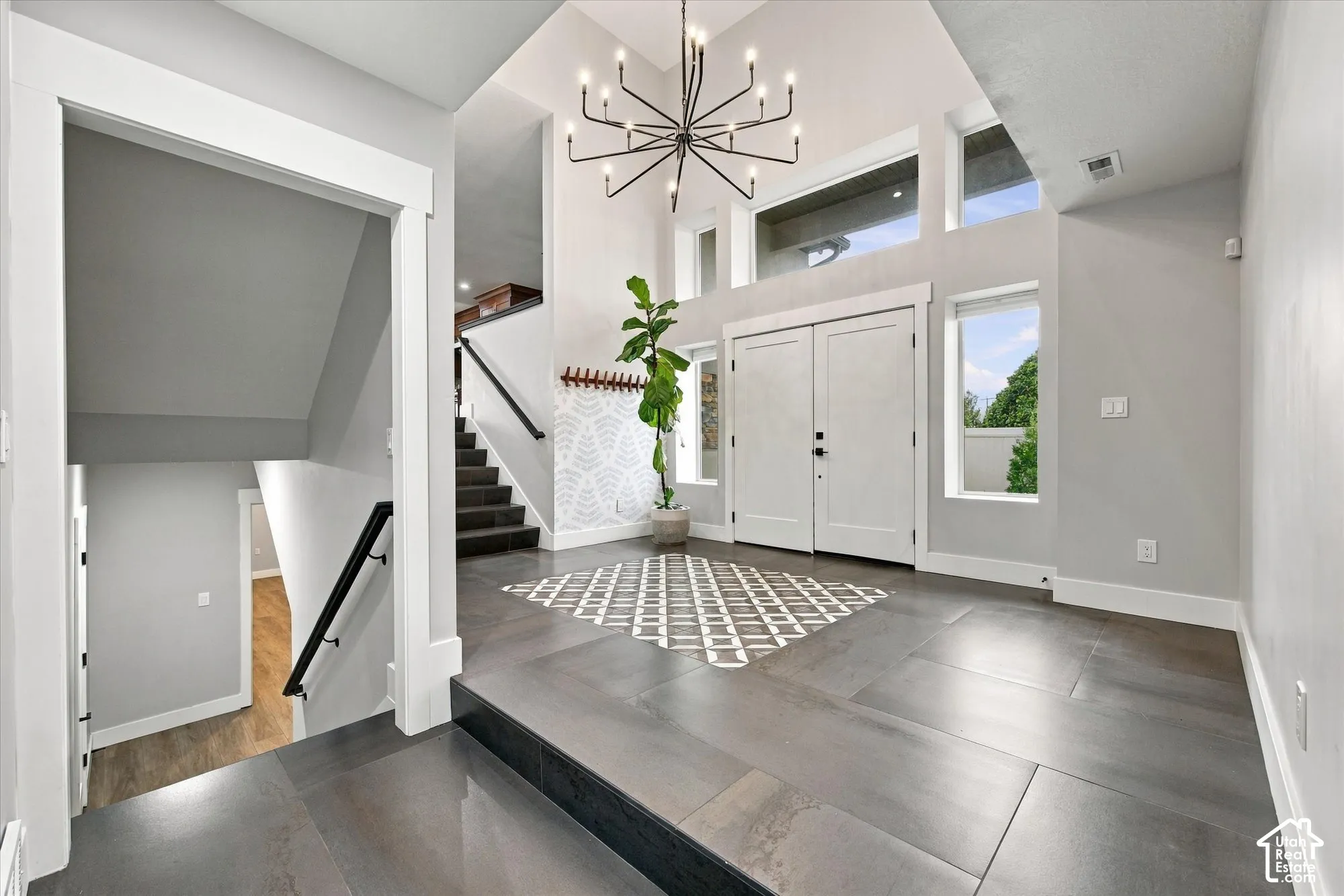 Foyer featuring vaulted ceilings, oversized tile flooring, double-entry doors, large transom windows, and a multi-arm chandelier