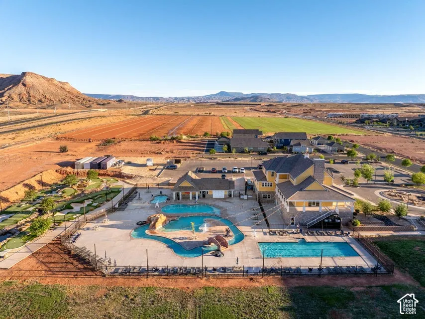 Recreational area featuring multi-level swimming pools, water features, a miniature golf course, and a clubhouse, set against a desert mountain backdrop