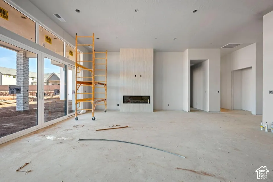 Floor-to-ceiling multi-panel glass sliding door system, linear fireplace with light-toned stone-finish surround, recessed ceiling lighting, and high ceilings