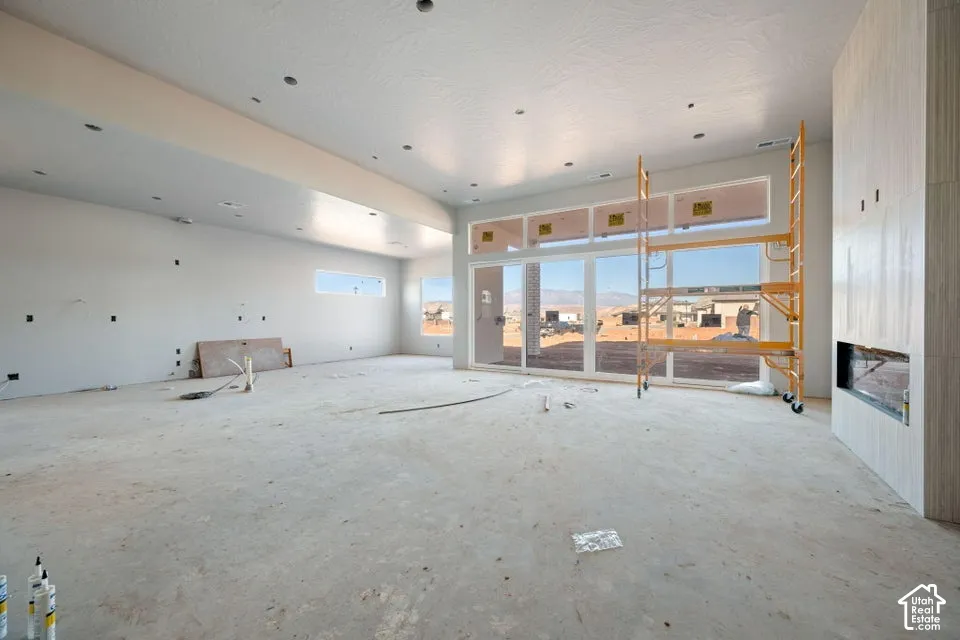 Open-concept interior featuring recessed lighting, a linear fireplace with vertical tile surround, and expansive multi-panel sliding glass doors with transom windows