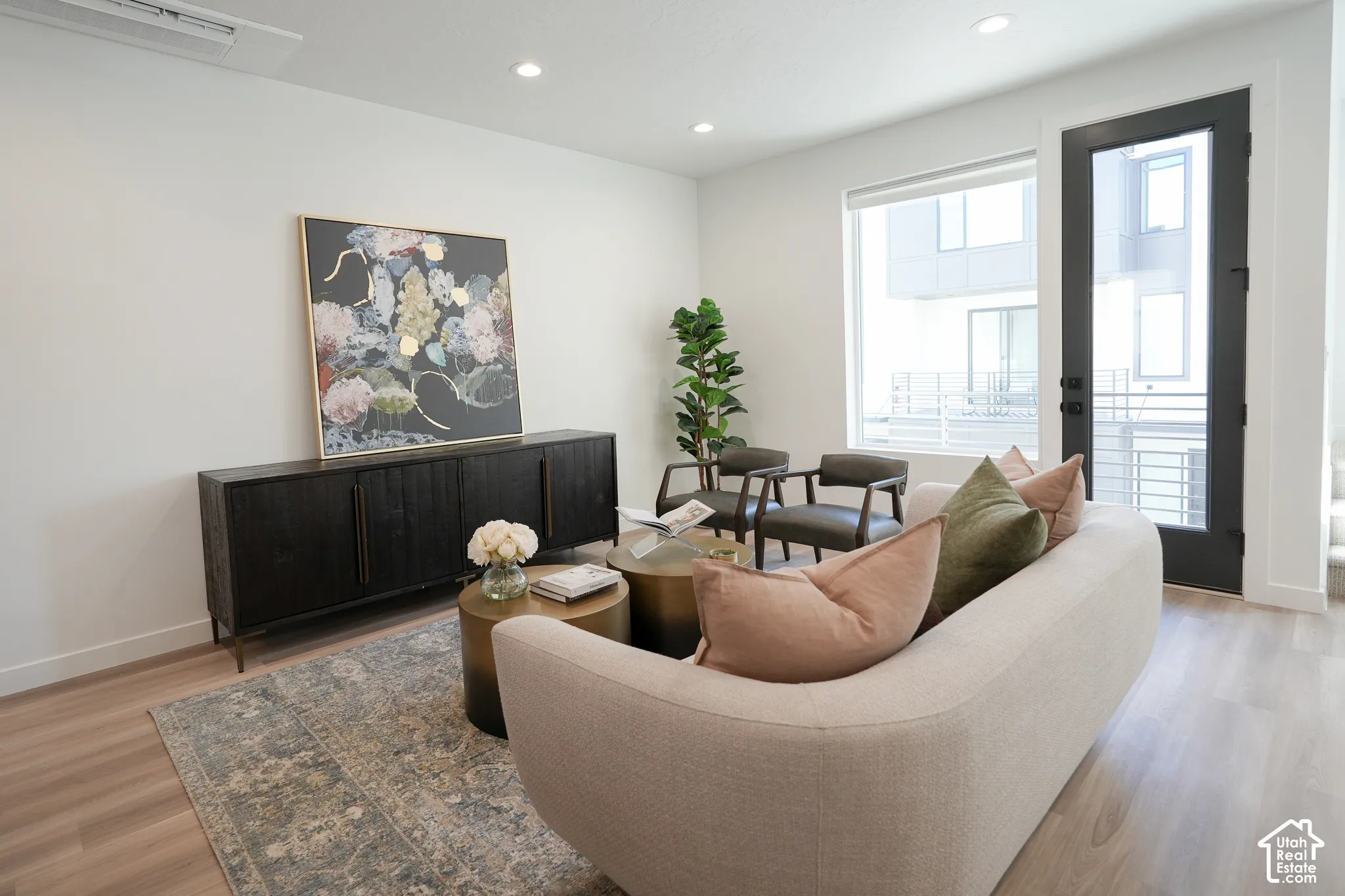 Wood-finish flooring, recessed lighting, and large windows with natural light, featuring a glass-paneled exterior door