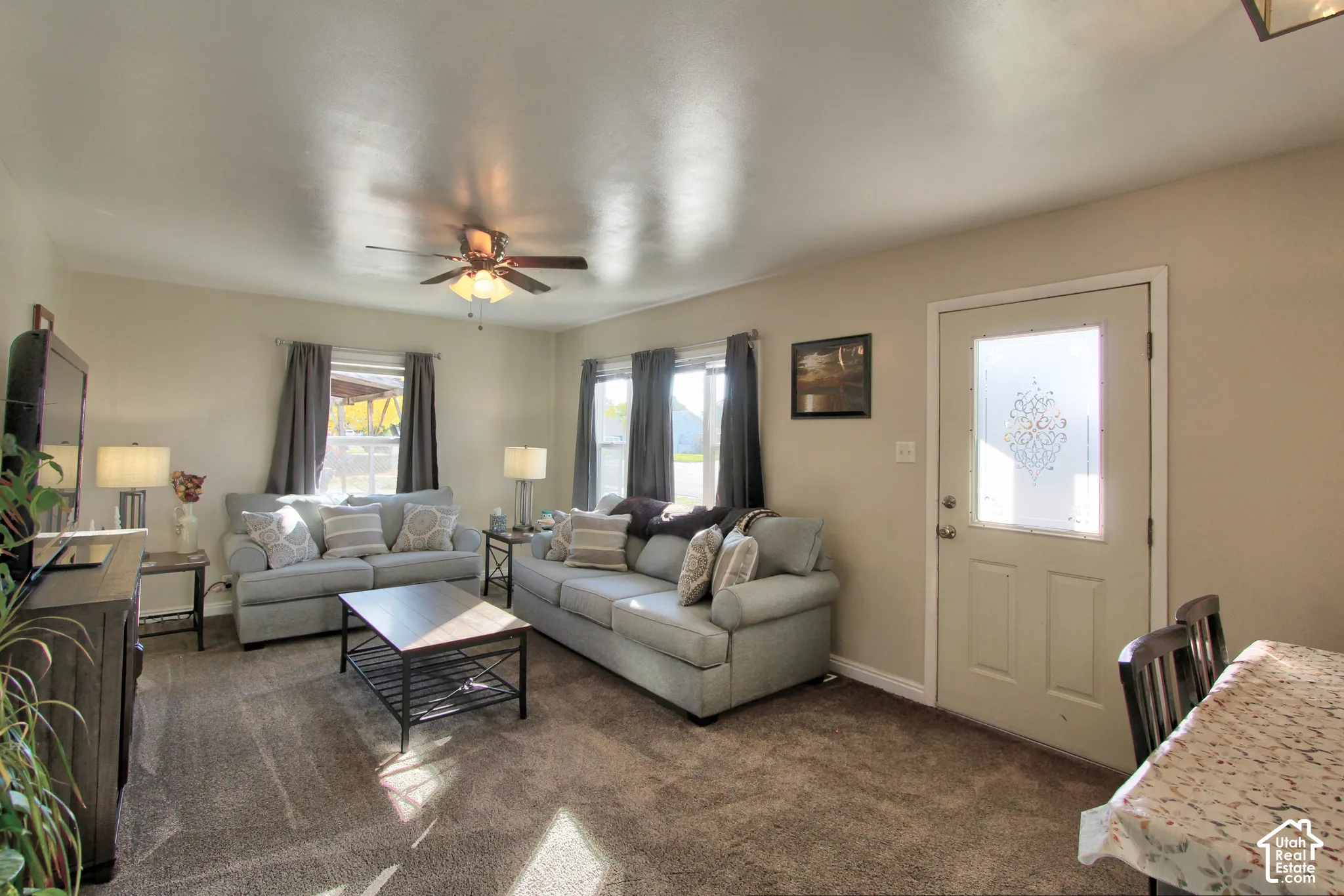 Neutral wall paint, plush carpeting, ceiling fan with integrated lighting, and a frosted glass-paneled entry door