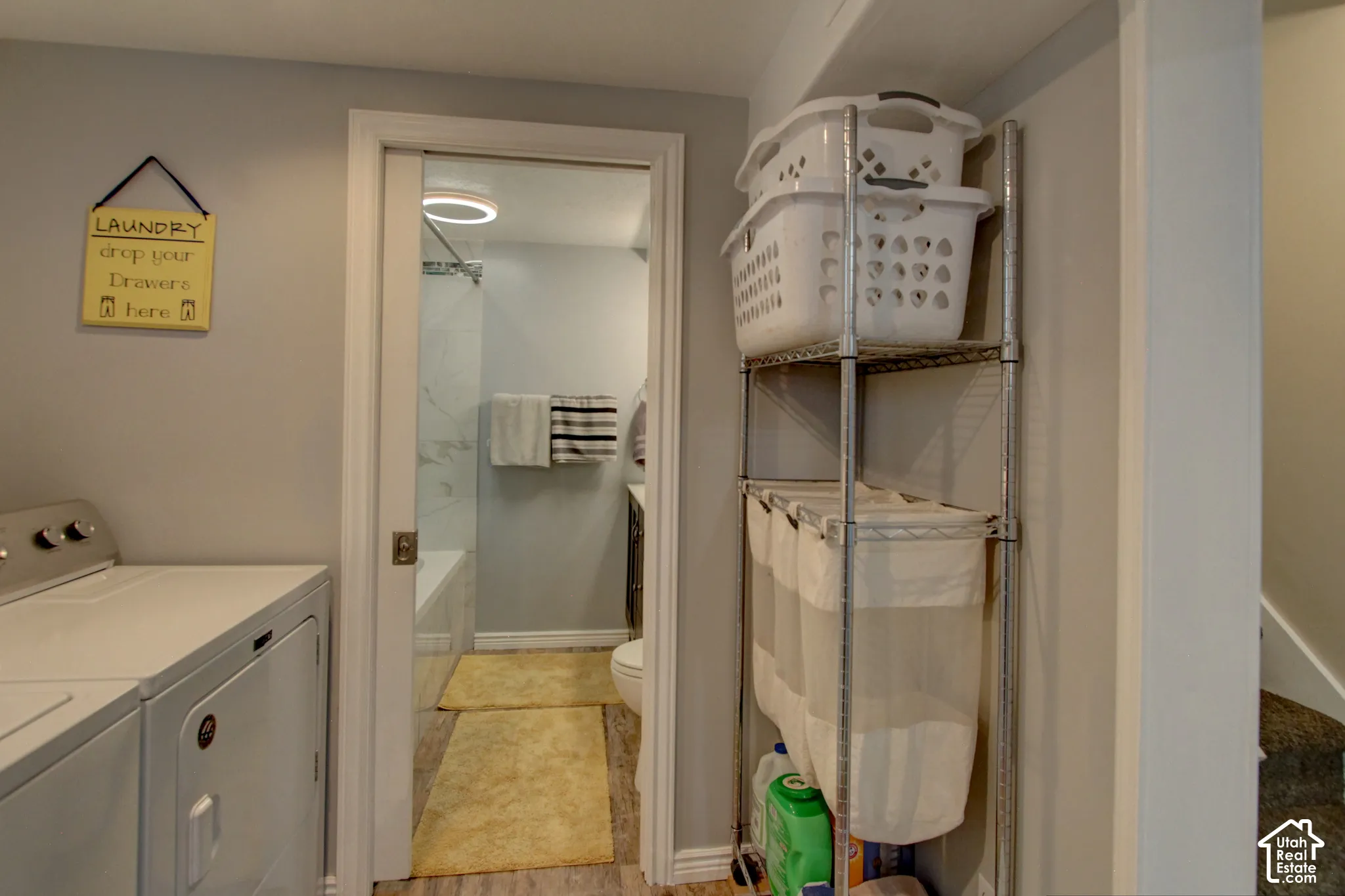 Laundry area featuring a pocket door entry, solid-surface flooring, and a bathtub with tile-surround walls