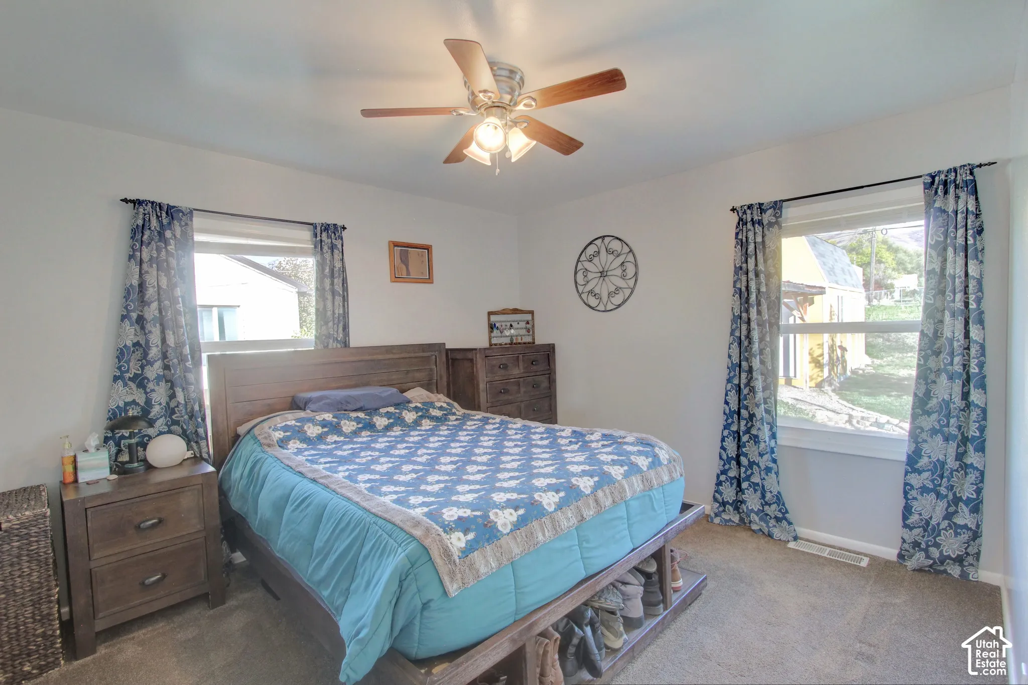 Neutral-toned room featuring wall-to-wall carpeting, two dual-pane windows, and a ceiling fan with integrated lighting