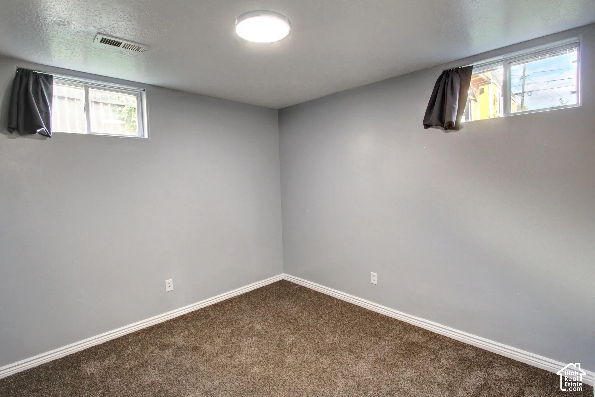 Neutral-toned interior room featuring wall-to-wall carpeting and two sliding windows