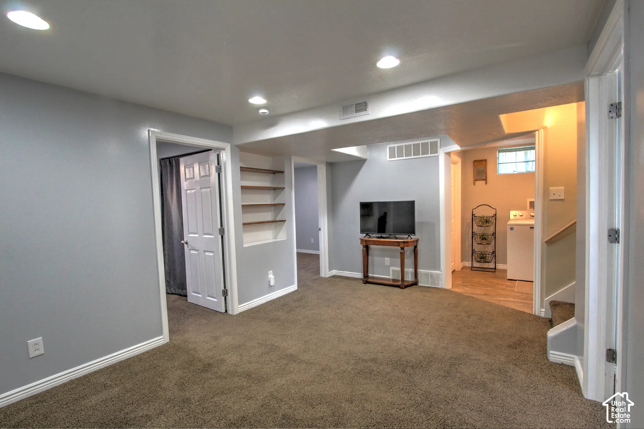 Downstairs family room featuring recessed lighting, wall-to-wall carpeting, built-in recessed shelving, and a multi-paneled door