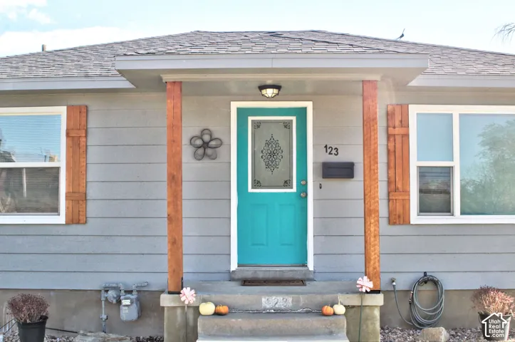 Exterior facade featuring horizontal siding, natural wood-finish support posts, decorative wood shutters, and an entry door with an ornate glass insert