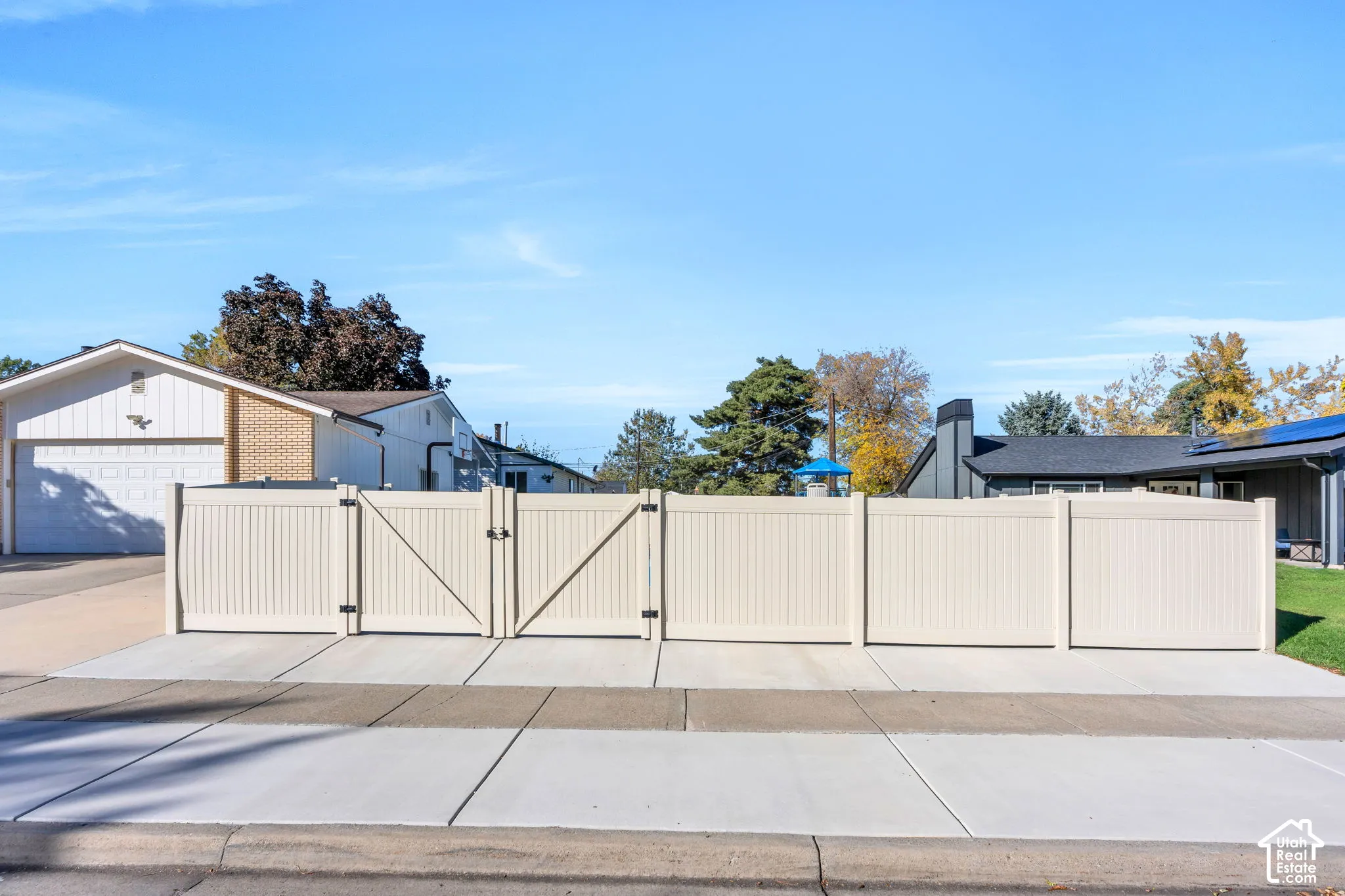 Vinyl privacy fencing with dual-gate entry and concrete driveway approach
