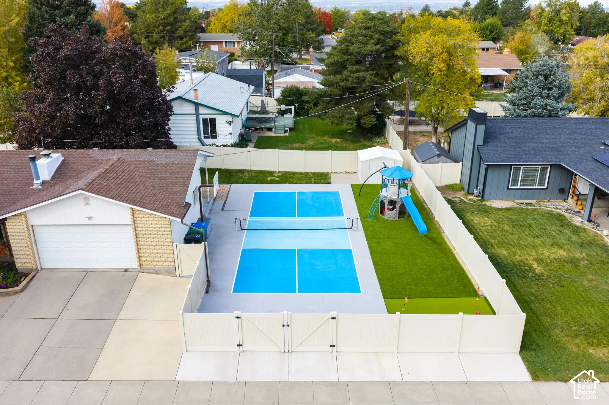 Private backyard featuring a dedicated pickleball court, synthetic turf area, and full perimeter vinyl fencing
