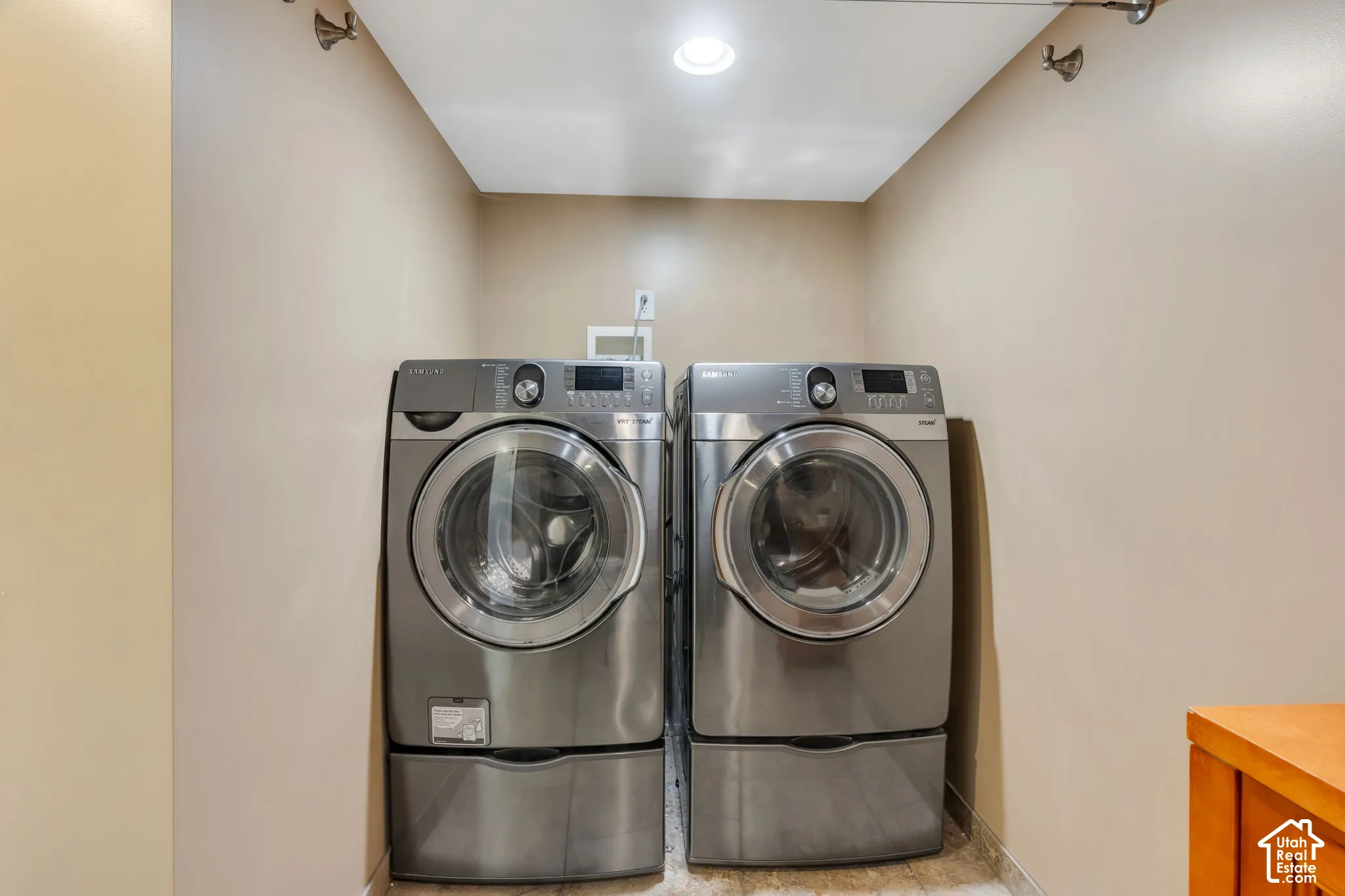 Laundry alcove featuring recessed ceiling lighting, stainless steel appliances, and wall-mounted garment hooks
