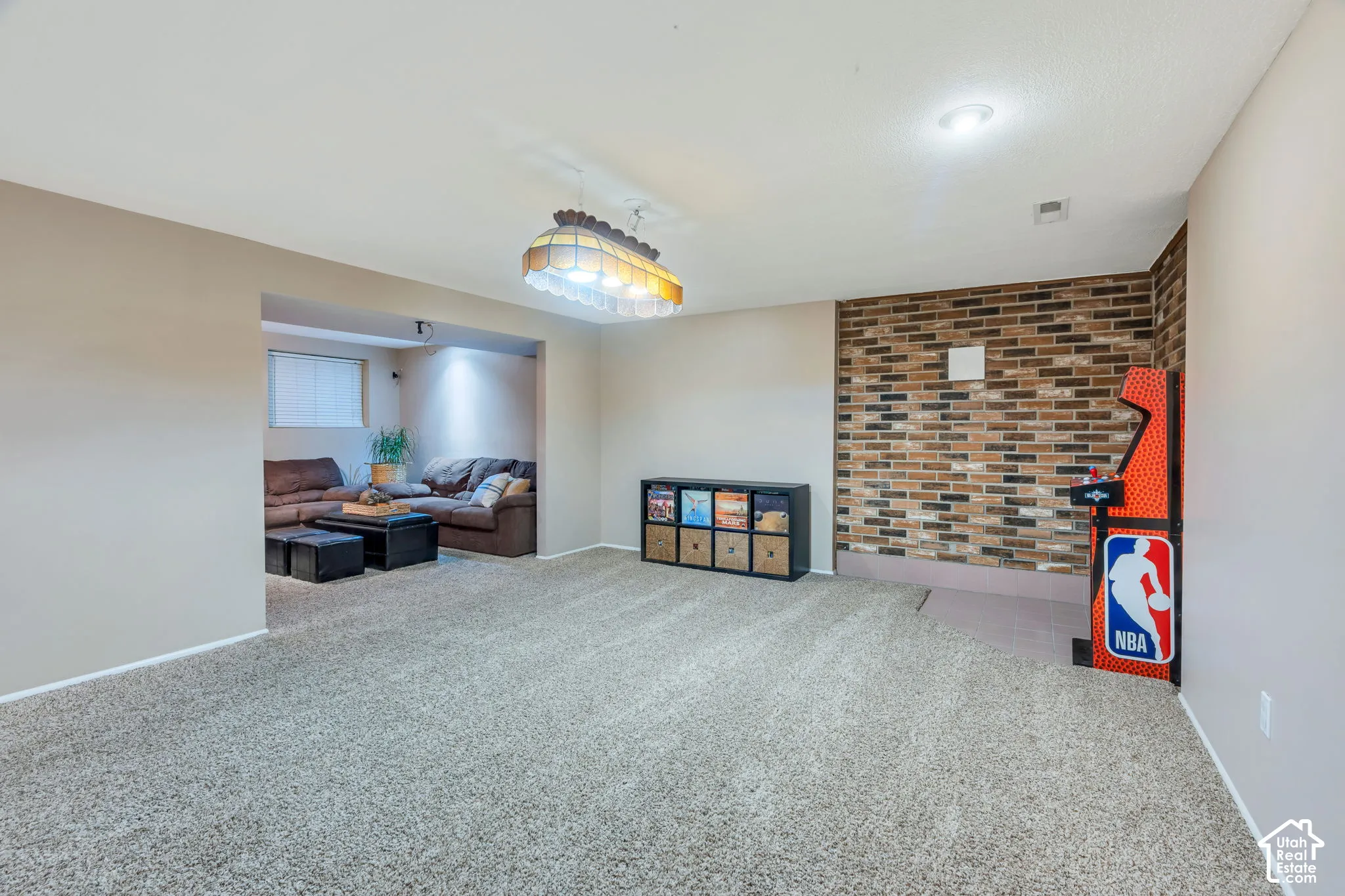 Expansive room featuring a brick-accent wall, recessed lighting, and a hanging pendant fixture