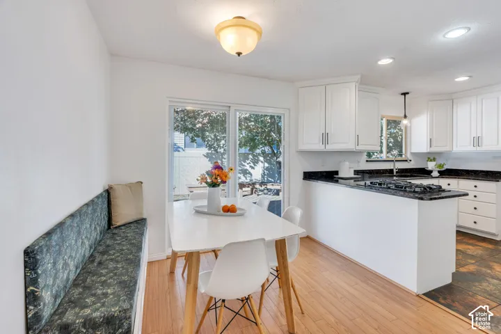 Kitchen featuring white shaker-style cabinetry, stone-finish countertops, built-in gas cooktop, wood-finish flooring, and sliding glass doors
