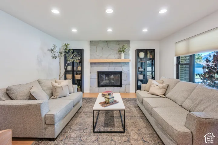 Full-height stone fireplace featuring a prominent wood mantel, integrated recessed lighting, and built-in glass-front cabinetry