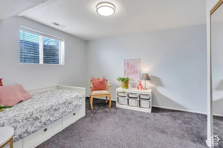 Neutral-toned room featuring wall-to-wall carpeting, recessed window with horizontal blinds, and a flush-mount ceiling light fixture