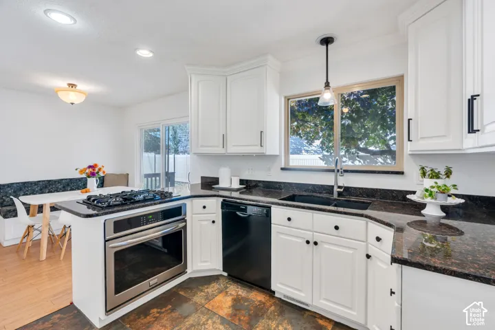Kitchen featuring white cabinetry, dark stone-finish countertops, black appliances including a built-in wall oven and dishwasher, tile flooring, and a sliding glass door