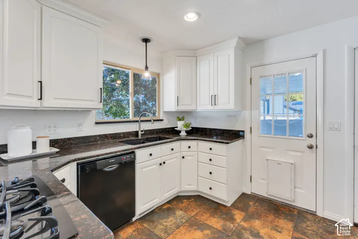 Kitchen featuring white cabinetry with matte black hardware, dark stone-finish countertops, tile flooring, and integrated dishwasher