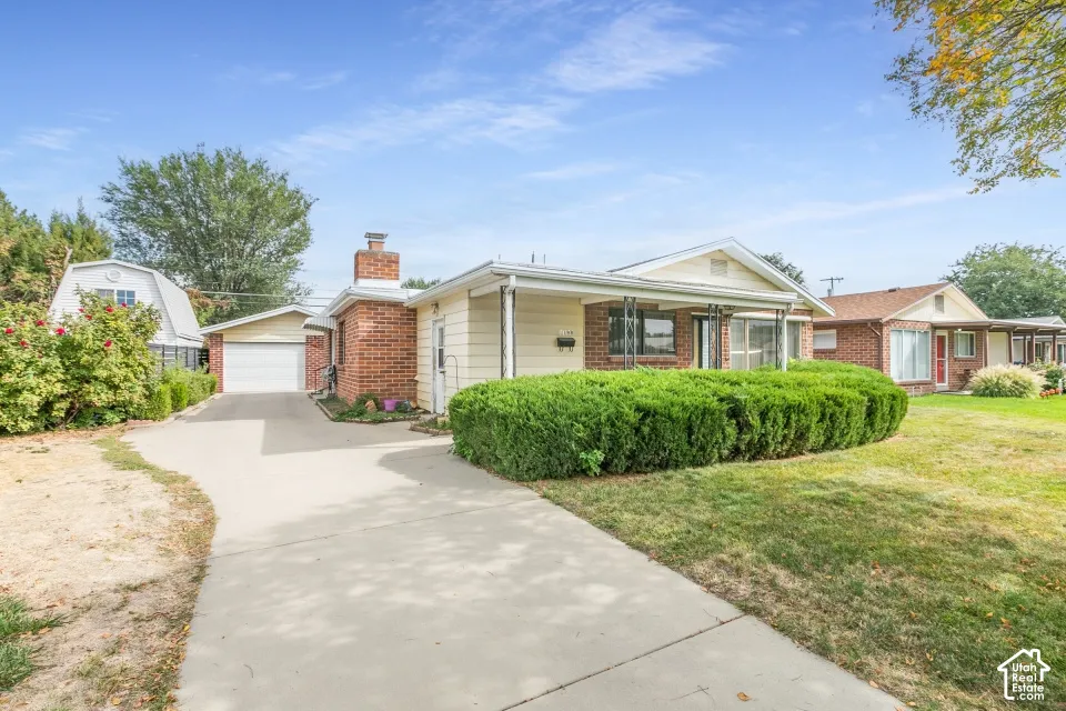 Single-story residence featuring a brick and siding exterior, front porch, detached two-car garage, and a concrete driveway