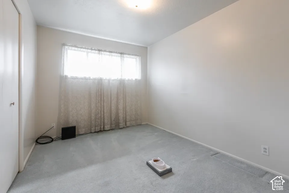 Neutral-toned interior space featuring wall-to-wall carpeting, an integrated reach-in closet with a sliding door, and a horizontal sliding window
