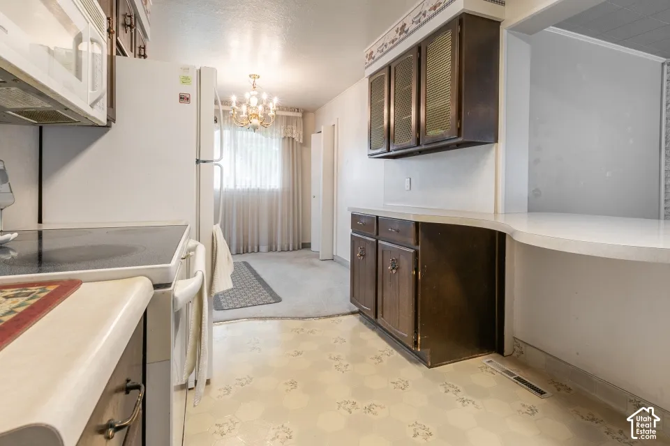 Kitchen featuring dark-toned cabinetry, a curved breakfast bar, patterned vinyl flooring, and a decorative hanging light fixture