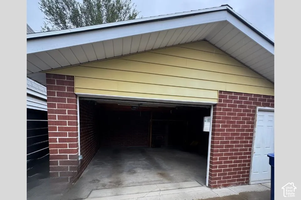 Detached garage featuring brick exterior walls, horizontal siding in the gable, and a concrete floor